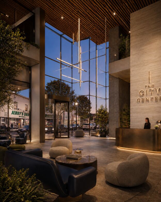 Conceptual rendering of the double-height glazed corner lobby with a wood-slat ceiling, bronze concierge desk, bouclé seating, and a 'The City Center' wall logo at dusk.