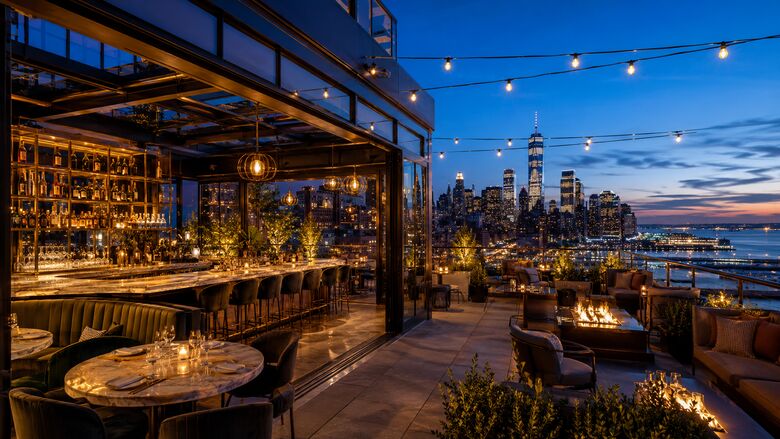 Conceptual rendering of a glass-enclosed rooftop restaurant and open terrace with fire features and skyline views at dusk.